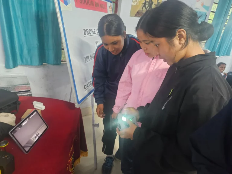 Participants inspecting an FPV drone and controller tablet up close during the workshop