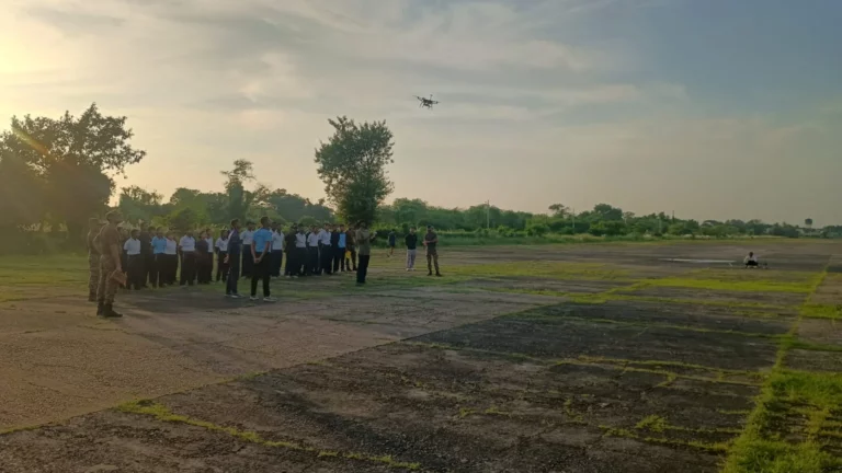 FPV drone flying over the Kancharapara airfield at dusk as participants watch