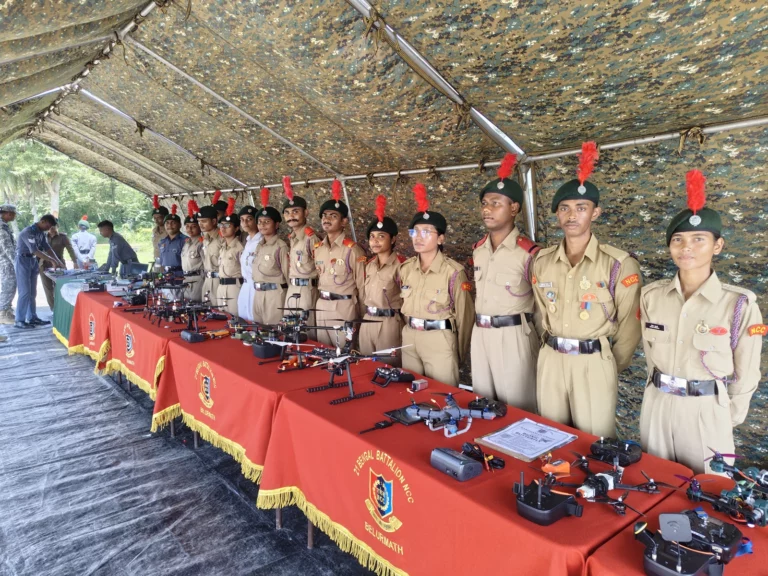 NCC cadets in uniform standing behind a display table of drones at the competition