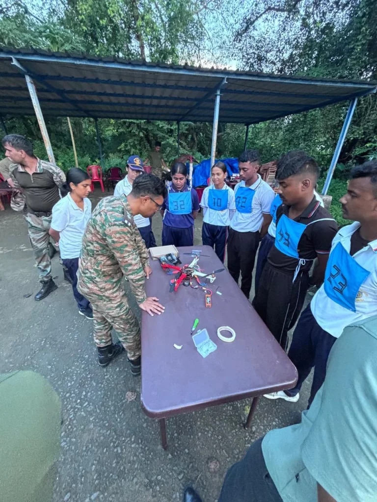 Army officer and participants inspecting drone parts on a table